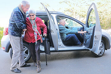 Photo d'une personne aidant une personne âgée à sortir d'une voiture. 