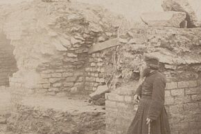 Photo en noir et blanc d'une personne devant une ruine.