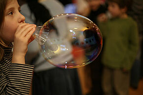 Photo d'un enfant faisant une grosse bulle de savon.